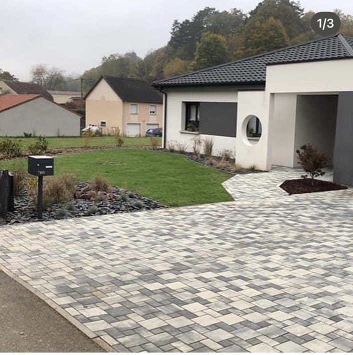 Allée en pavés gris nuancés, pelouse neuve et massifs de graminées devant une maison